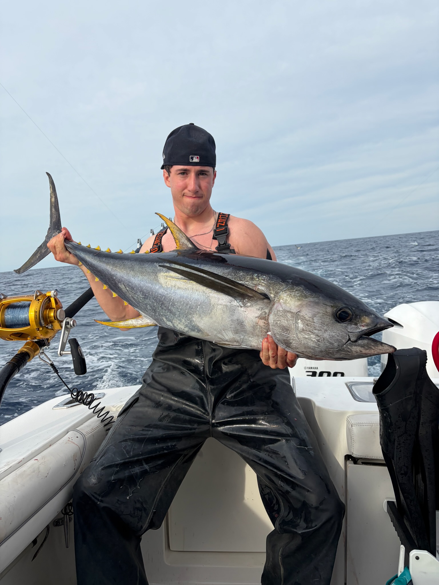 Angler in waders holding large yellowfin tuna