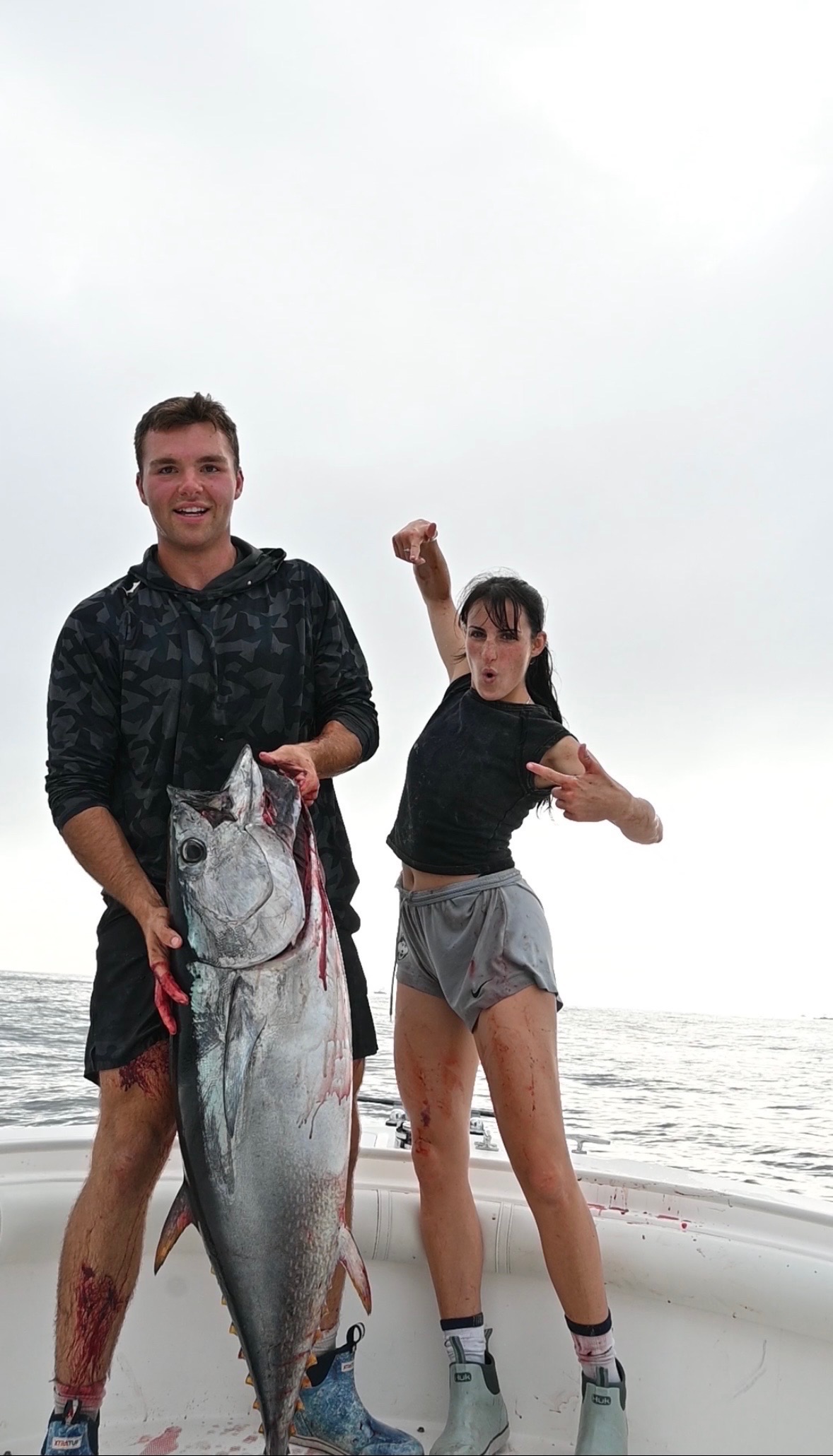 Two anglers posing with large bluefin tuna on foggy day