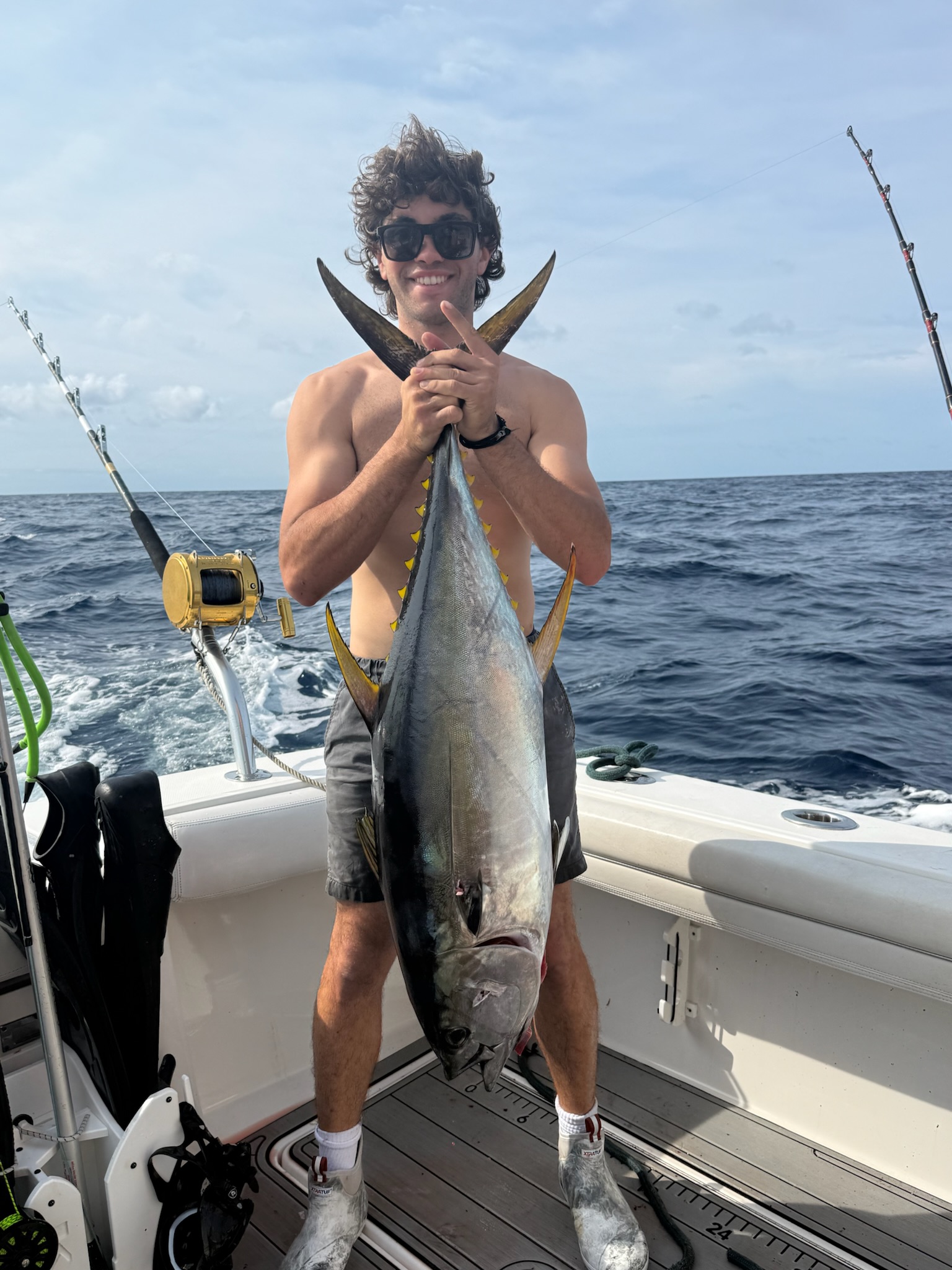 Angler holding yellowfin tuna by tail offshore