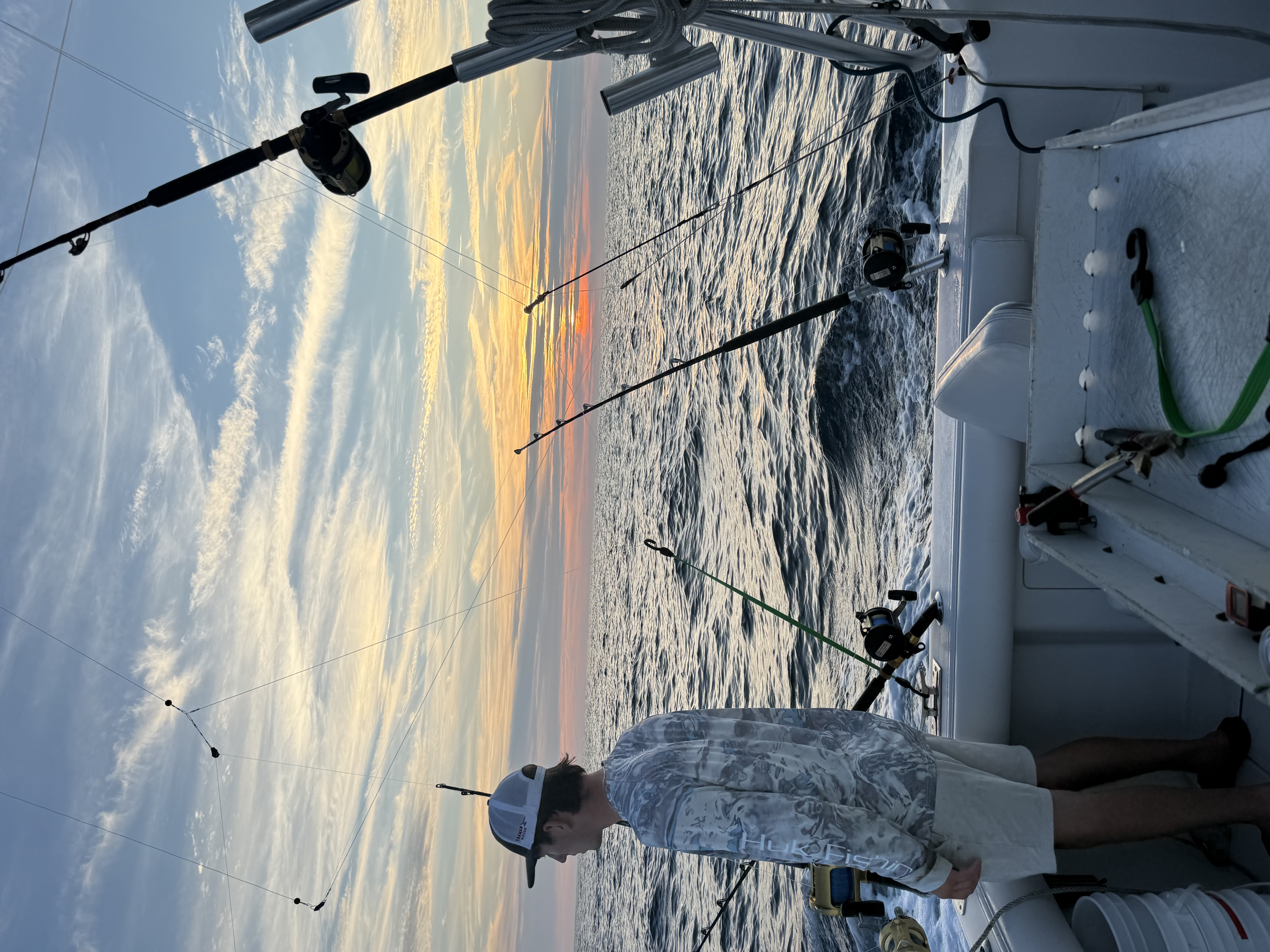 Angler watching sunset with trolling spread offshore on Albemarle