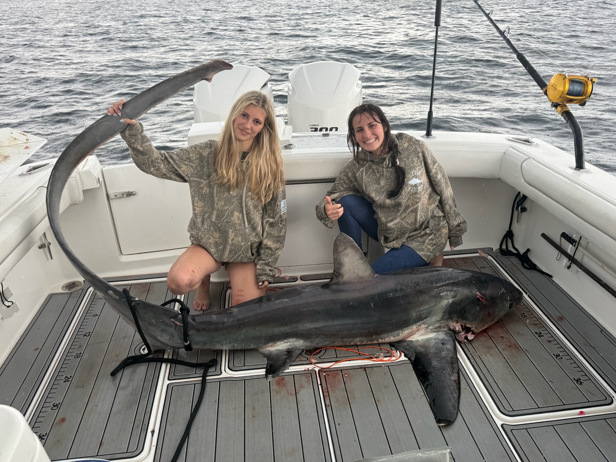 Two women with thresher shark on Albemarle deck