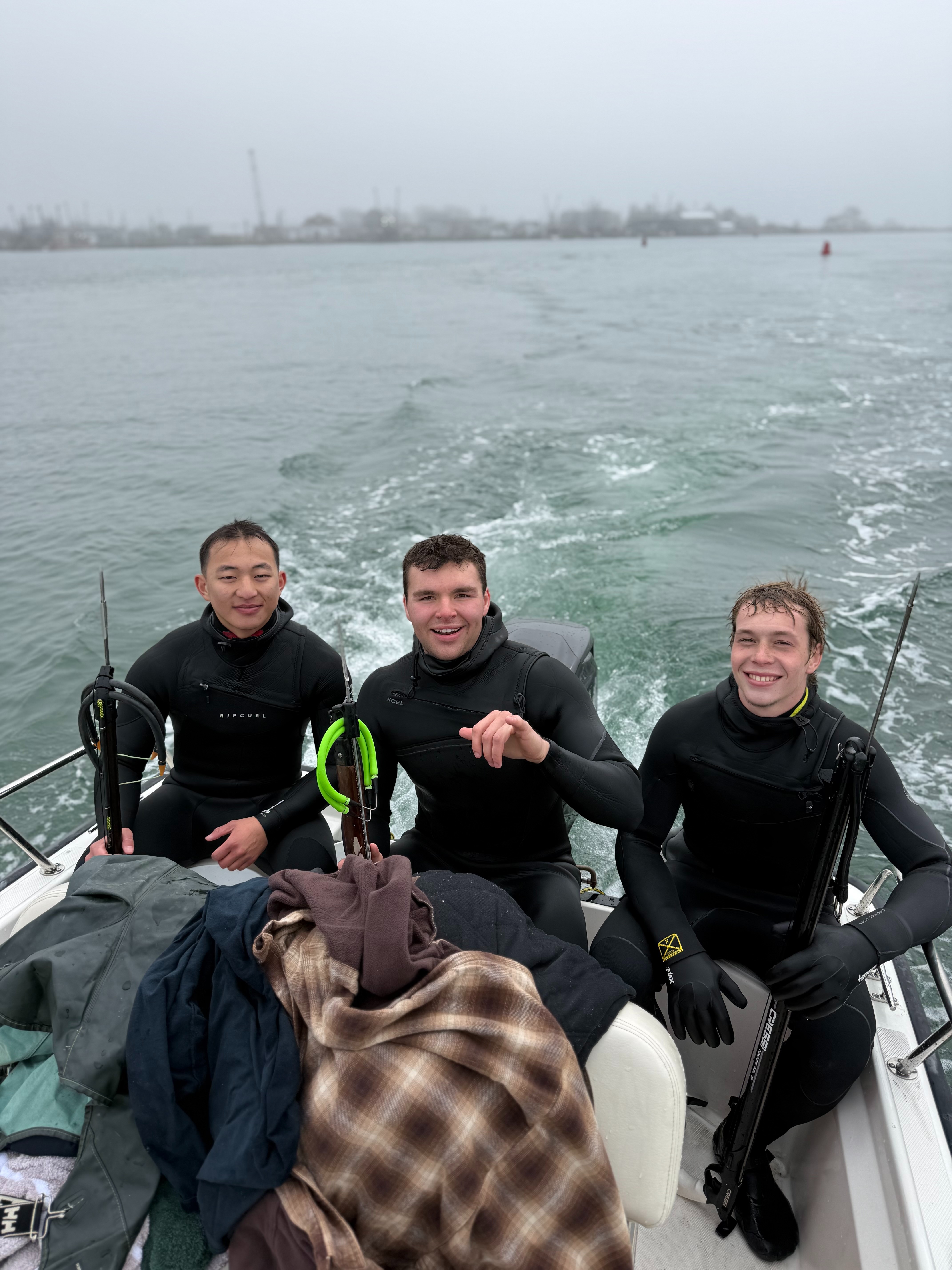 Three divers in wetsuits on a foggy run
