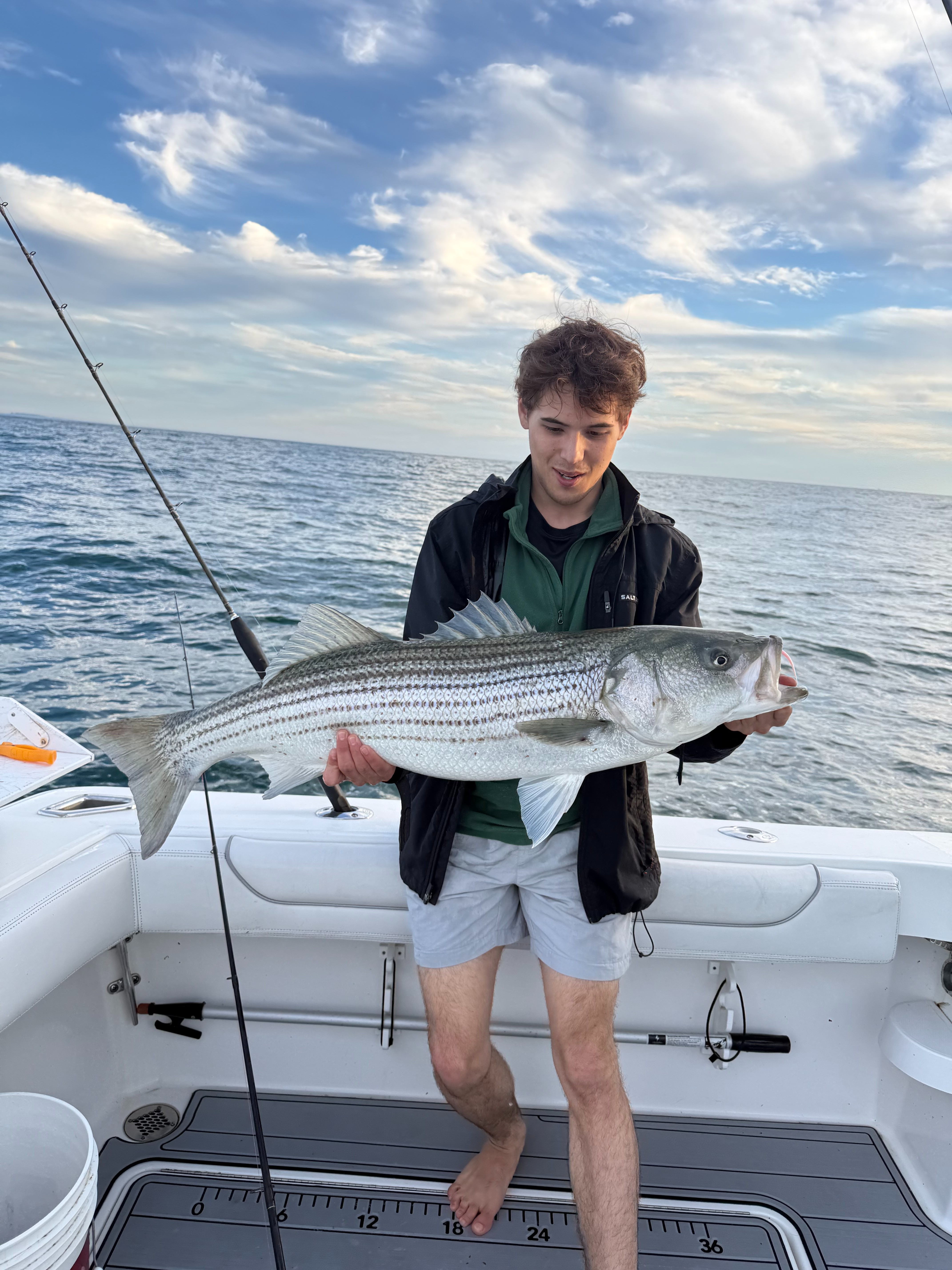 Angler with a striped bass under dramatic clouds