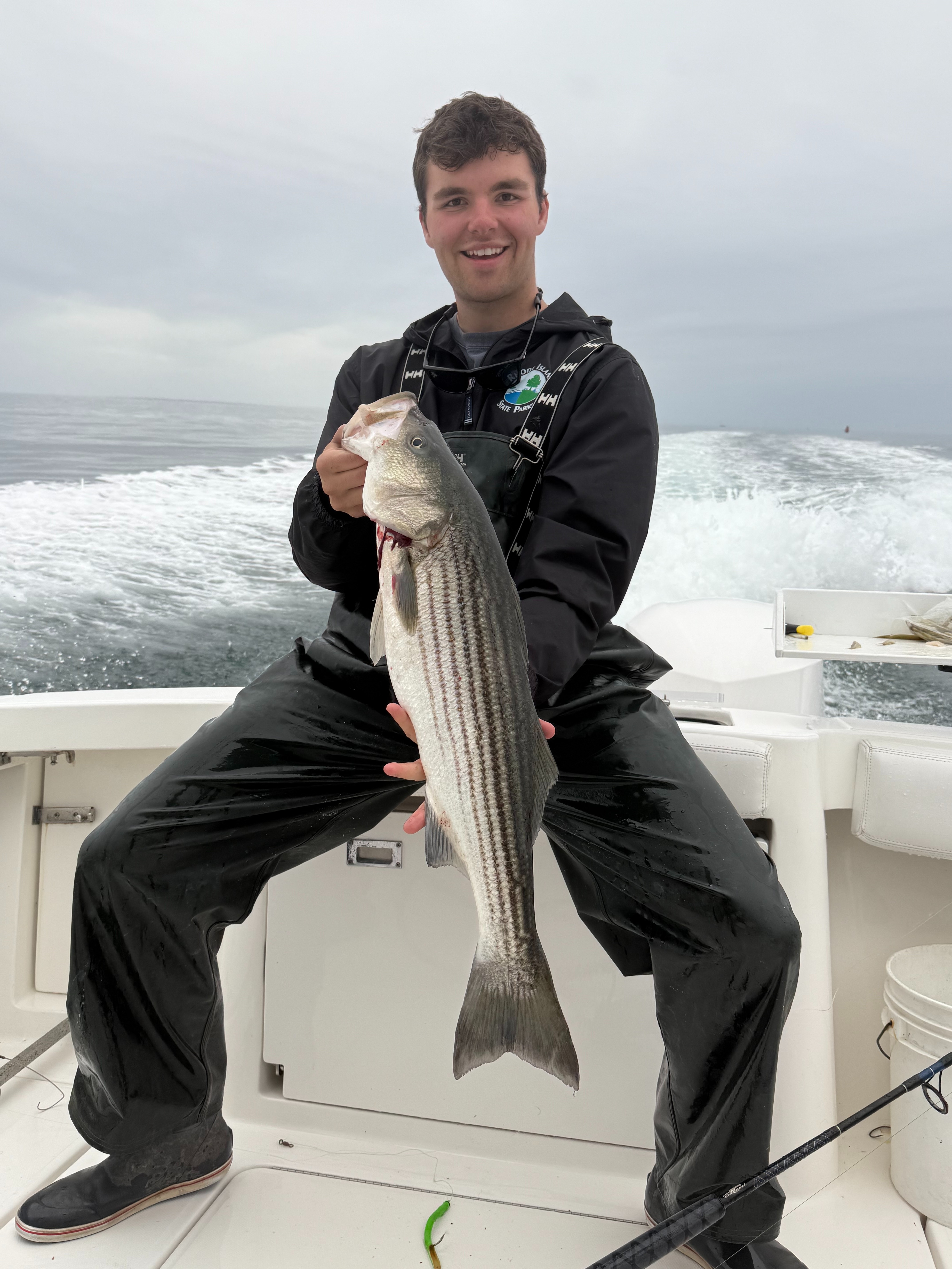 Angler holding a large striped bass on the boat